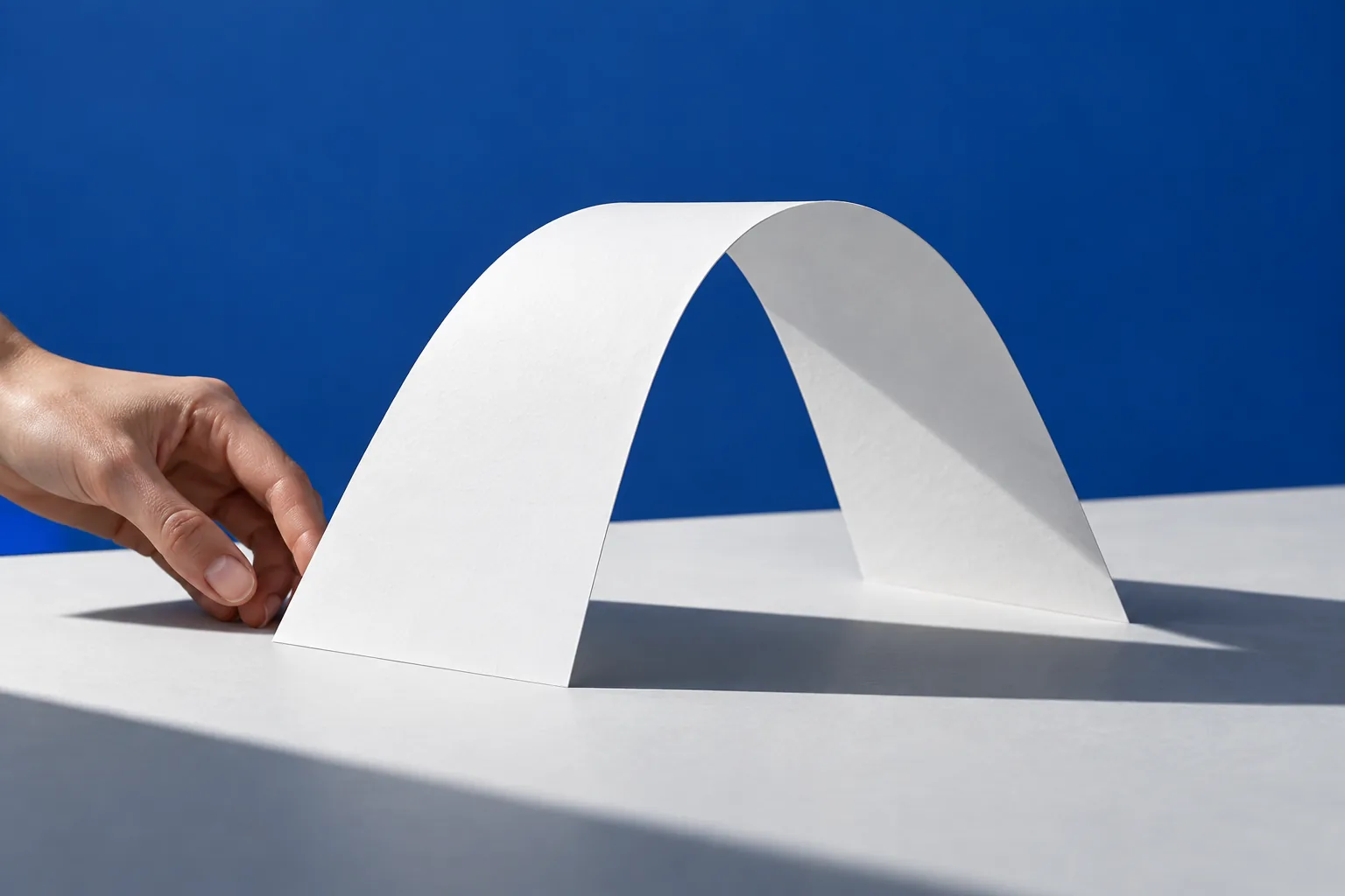 A sculpturally folded white sheet casting a geometric shadow